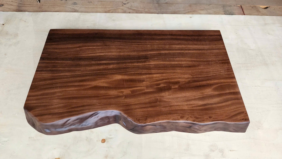 Finished solid wood live edge tabletop with rich grain and a natural curved edge in the Woodfurnist workshop