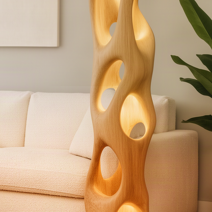 Close-up of the Ambera Oak floor lamp showing smooth carved openings, natural wood grain and warm light glowing inside