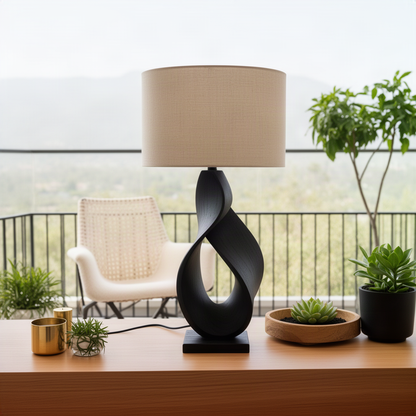 Infinia sculptural table lamp in Black solid wood with a twisted ribbon base on a desk by a balcony view