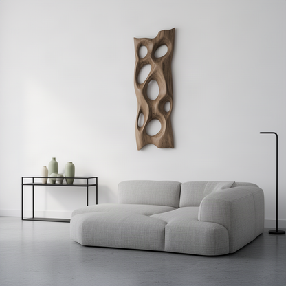 Porella organic wood wall sculpture seen at an angle above a grey sofa, tall carved panel with oval cut-throughs